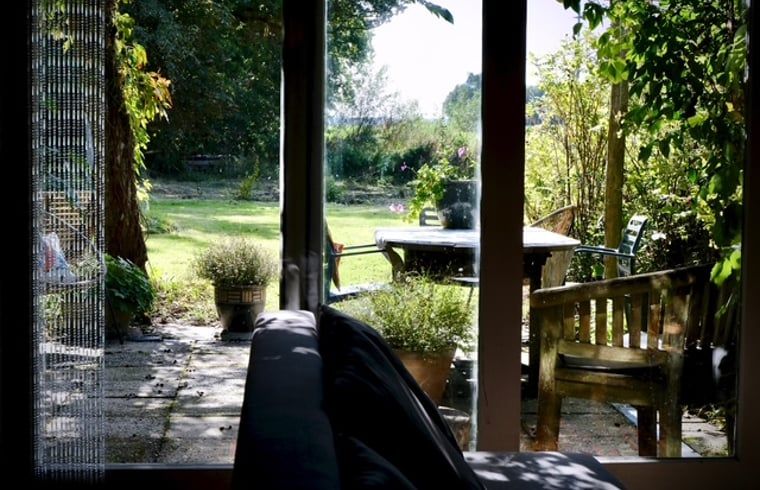 Uitzicht op de tuin vanuit de woonkamer van Vakantiehuisje in Donkerbroek, Friesland.