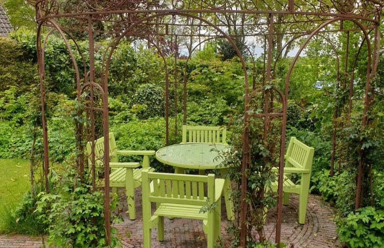 Geniet van de rust op het groene terras bij Vakantiehuis in Idskenhuizen, omringd door weelderige natuur op het Friese platteland.