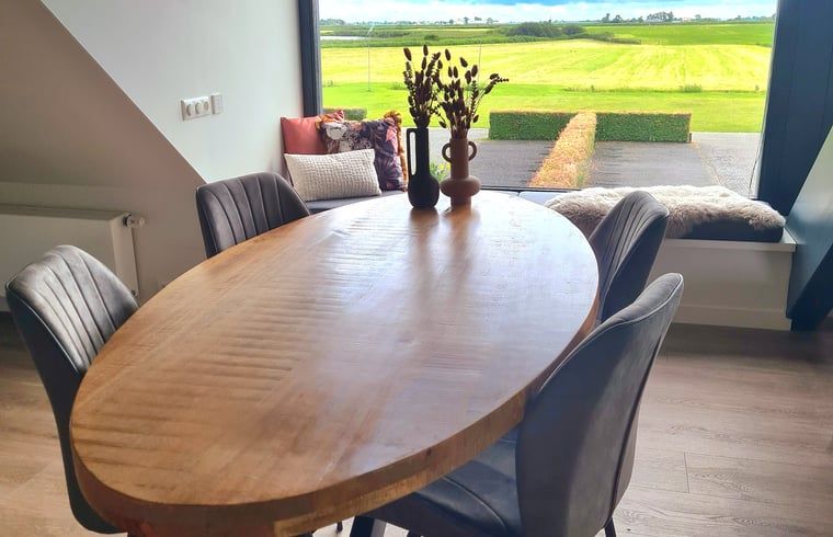 Houten eettafel in Vakantiehuisje in Westhem met panoramisch uitzicht op het Friese platteland, Friesland.