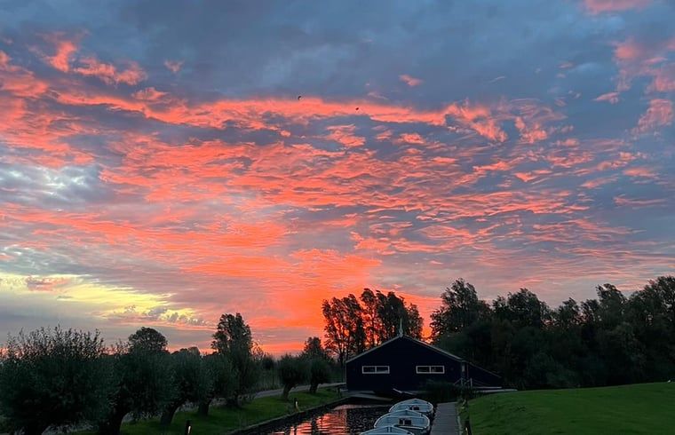 Sfeervolle zonsondergang boven Vakantiehuisje in Westhem, omgeven door natuur, Friesland.