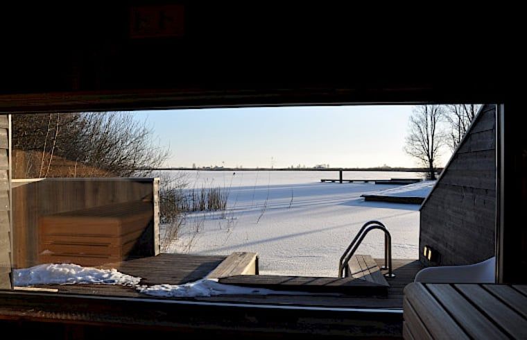 Uitzicht op bevroren landschap vanuit sauna in Vakantiehuisje in Westhem, Friesland.