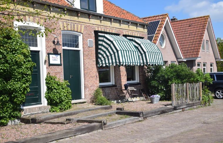 Charmante gevel van Vakantiehuisje in Munnekeburen, Friesland met groene luifel en bakstenen details.