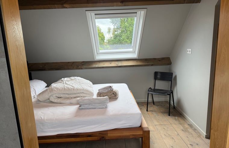 Slaapkamer met houten bed in Vakantiehuis in Surhuisterveen, knusse sfeer, Friesland.