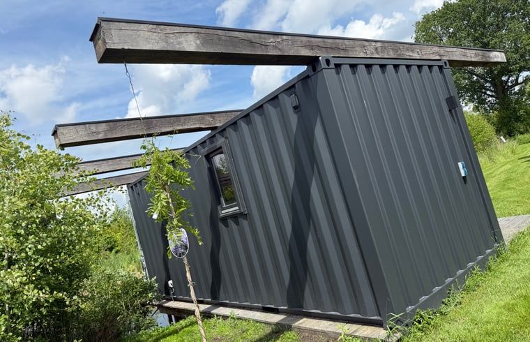 Zijaanzicht van het vakantiehuis in Surhuisterveen te midden van het groene Friese platteland.