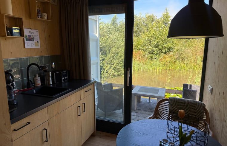 Keuken met uitzicht op terras en natuur bij Huisje in Surhuisterveen, Friesland.