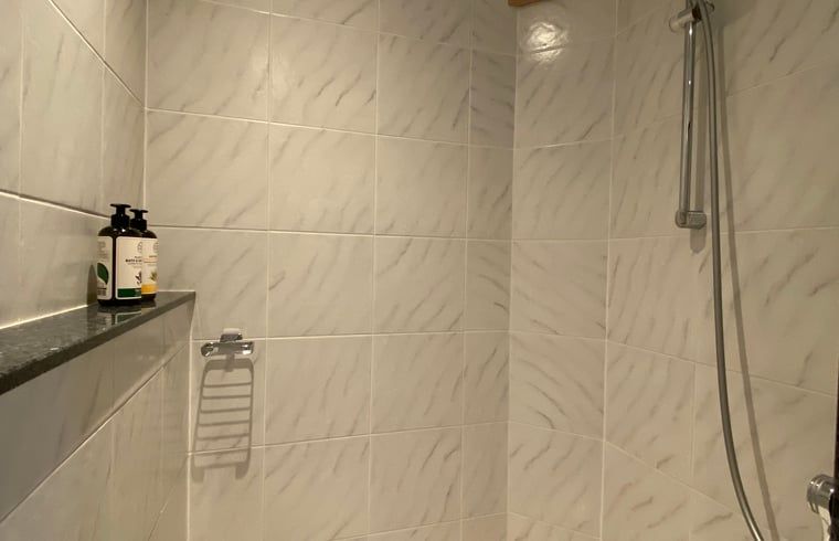 Ruime douche in Vakantiehuis in De Hoeve, Friesland, met moderne tegelafwerking.