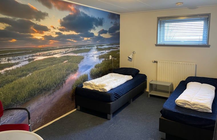 Schlafzimmer mit Waschbecken im Ferienhaus in Hegebeintum, mit Blick auf die friesische Landschaft.