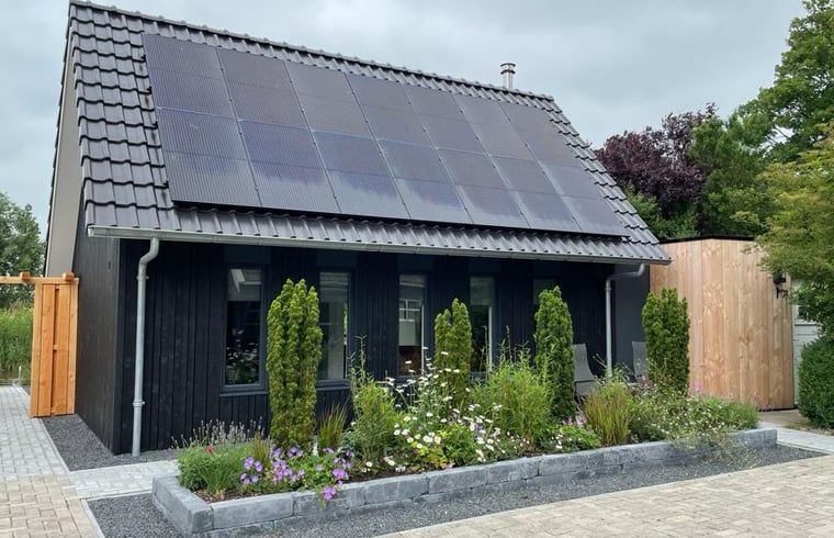 Duurzaam vakantiehuis met zonnepanelen in Bartlehiem, omgeven door tuin op het Friese platteland.