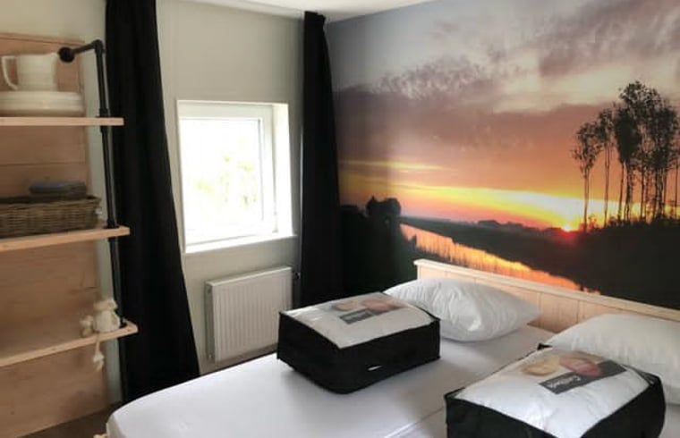 Slaapkamer in Vakantiehuisje in Bartlehiem met schilderachtige muurschildering van zonsondergang.