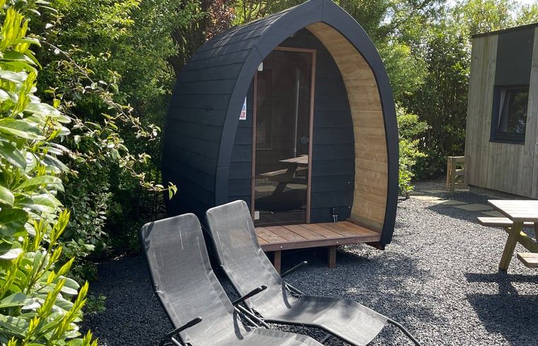 Uniek houten huisje met ligstoelen bij Vakantiehuisje in Bartlehiem, ideaal voor ontspanning.