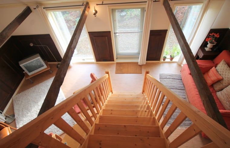 Gezellige binnenruimte van Huisje in Readtsjerk op het Friese platteland, met houten trap en knusse zithoek voor een ontspannen verblijf.