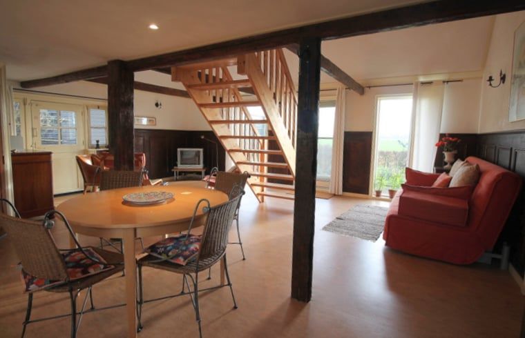 Gezellige woonkamer in Huisje in Readtsjerk, vakantiehuis op het Friese platteland met houten balken en landelijke charme.
