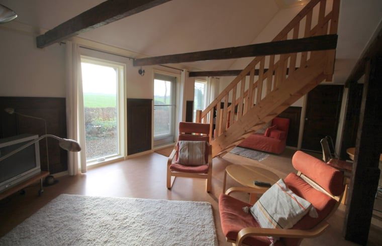 Gezellige woonkamer van Huisje in Readtsjerk, Friesland, met comfortabele stoelen en uitzicht op het Friese platteland.