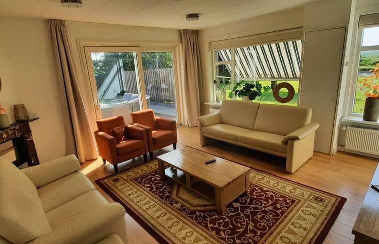 Gemuetliches Wohnzimmer des Ferienhauses in Oldelamer, Ferienhaus auf dem friesischen Land, mit grosszuegiger Sitzecke und Blick auf den Garten.