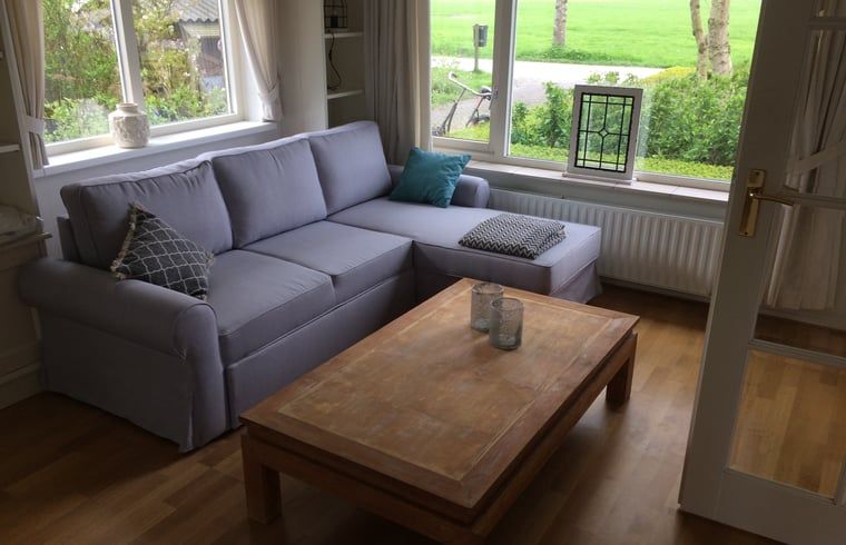 Gemuetliche Sitzecke im Ferienhaus in Nes, Friesland, mit Blick auf die friesische Landschaft.