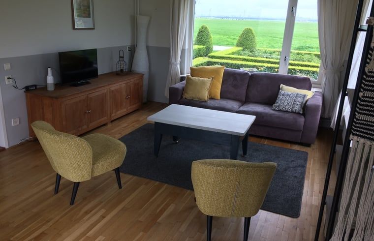 Stilvolles Wohnzimmer im Ferienhaus in Nes, Friesland, mit Blick auf die gruene Landschaft.