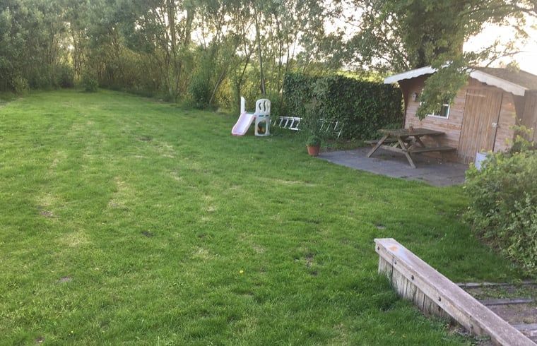 Geraeumiger Garten mit Spielgeraeten im Ferienhaus in Nes, Friesland, ideal fuer Kinder.