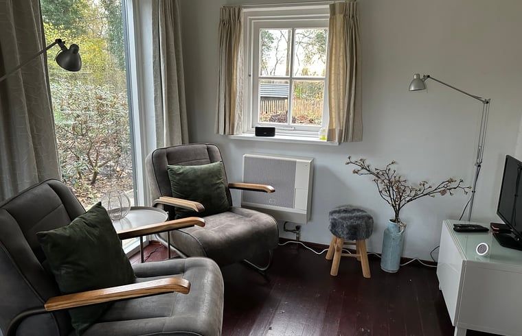 Gemuetliches Wohnzimmer im Ferienhaus in Nijeholtpade, Friesland, mit bequemen Stuehlen und Blick auf die friesische Landschaft.