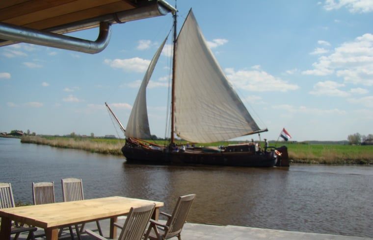 Sailboat sails past the terrace of Huisje in Jannum near Dokkum, located in Friesland.