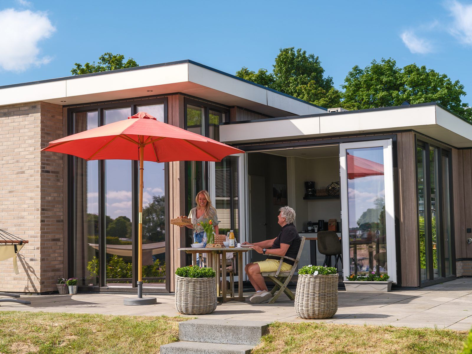 Geniessen Sie die Terrasse von Cube XL mit Sauna, einem modernen Ferienhaus fuer 4 Personen in Lathum, Gelderland, umgeben von Natur.