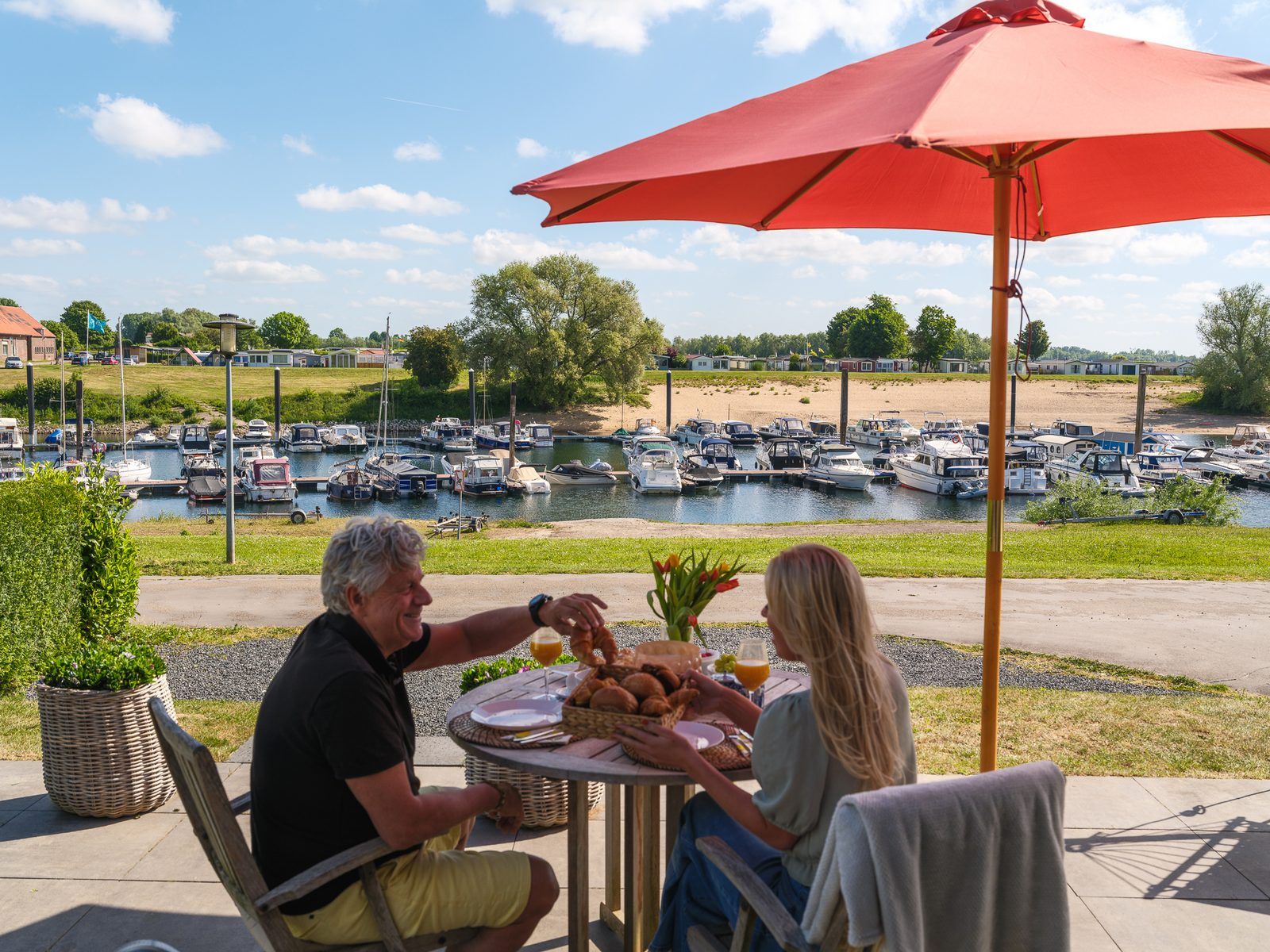Geniessen Sie das Fruehstueck auf der Terrasse des Cube XL mit Sauna in Lathum, Gelderland, mit Blick auf den Jachthafen und die Natur.