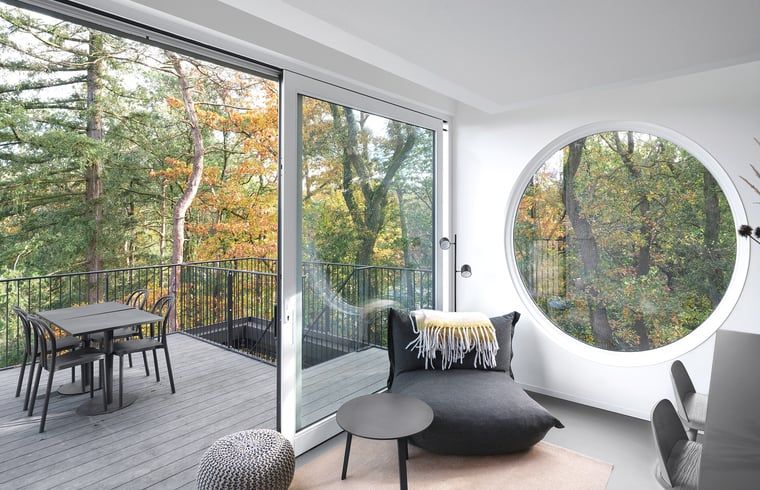 Helle Einrichtung des Ferienhauses in Arnheim mit Zugang zum Balkon und Blick auf die Natur.