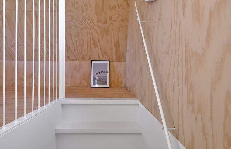 Treppe zum Obergeschoss in einem Ferienhaus in Arnheim mit hoelzerner und weisser Oberflaeche.