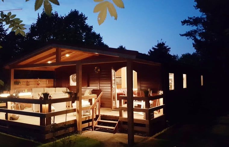Atmospheric illuminated vacation home in Wolfheze by night, located in the Rivierengebied, Gelderland.