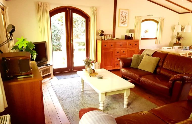 Cozy living room of vacation home in Wolfheze with access to the terrace, located in Gelderland.