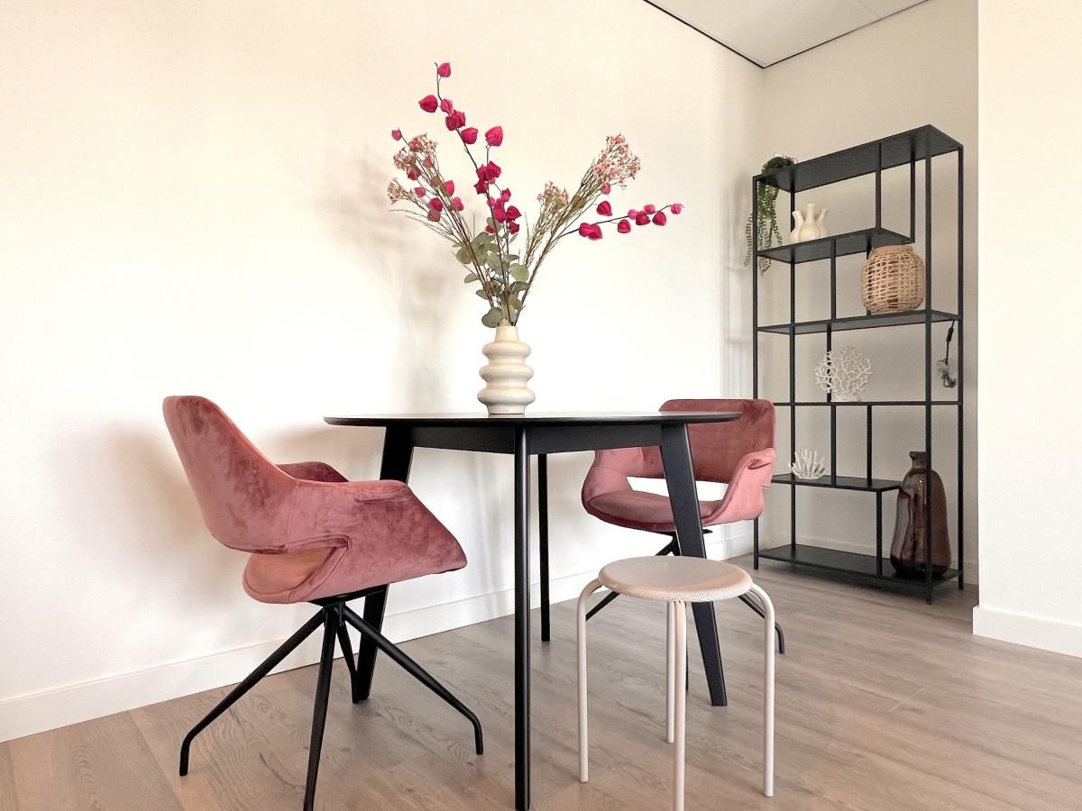 Essecke im Ferienhaus Havenzicht, Maasbommel, mit eleganten rosafarbenen Stuehlen und Blumenschmuck im Rivierengebied, Gelderland.