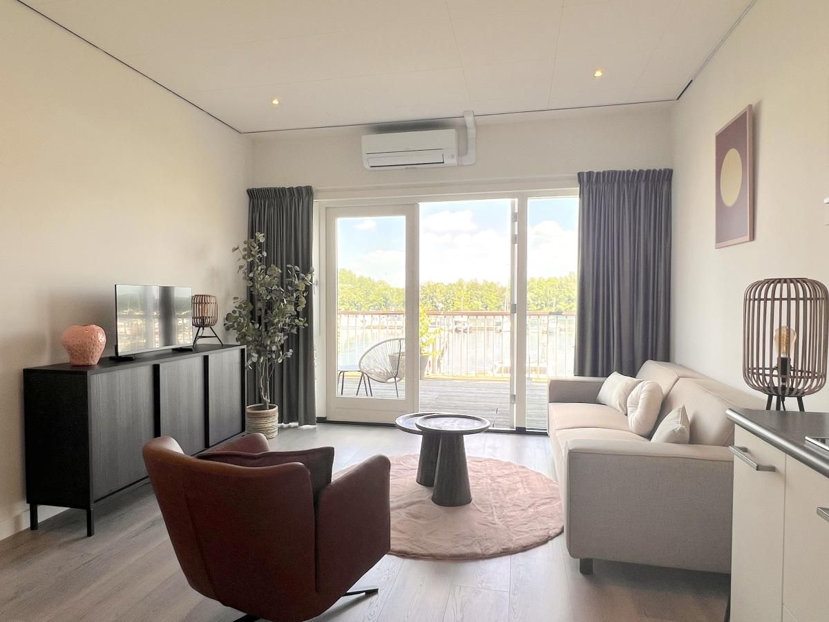 Helles Wohnzimmer mit Blick auf das Wasser im Ferienhaus Havenzicht, Maasbommel, Rivierengebied, Gelderland.