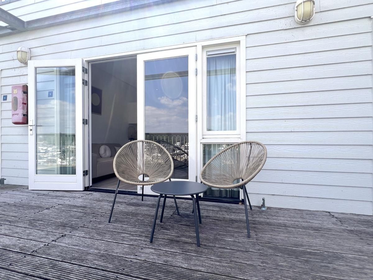 Terrasse mit Stuehlen im Ferienhaus Havenzicht, Maasbommel, mit Blick auf den Jachthafen in Rivierengebied, Gelderland.