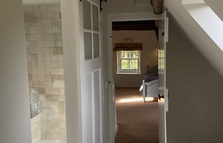 Lichte doorgang naar slaapkamer in vakantiehuisje in Neerijnen, met uitzicht op de tuin in het Rivierengebied.