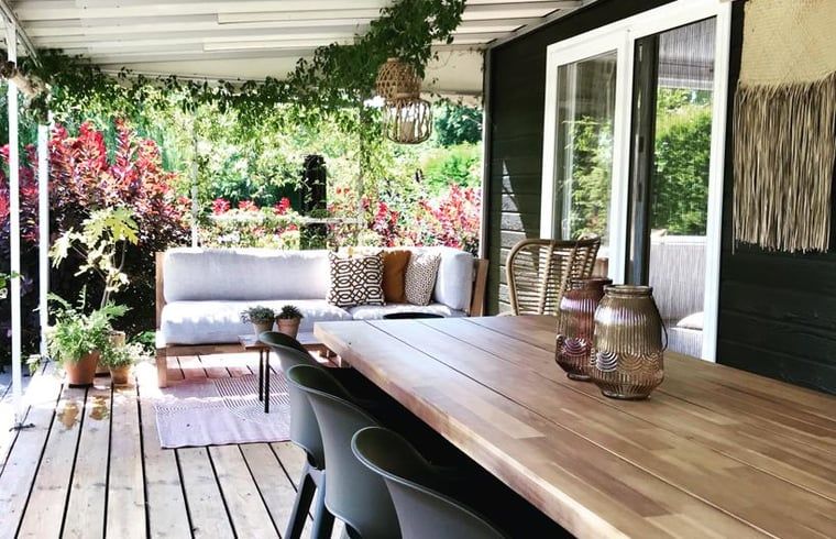 Geniet van de veranda van Huisje in Gellicum, een vakantiehuis in het Rivierengebied van Gelderland, omringd door groen en rust.