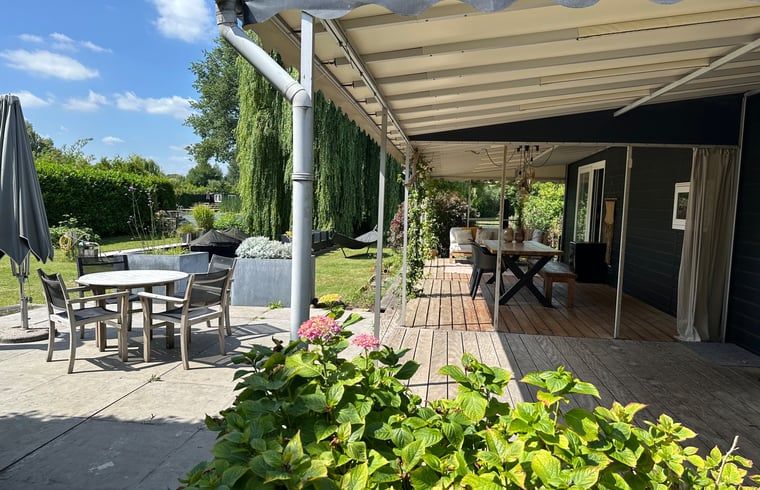 Geniet van de ruime veranda van Huisje in Gellicum, een vakantiehuis in het groene Rivierengebied van Gelderland.