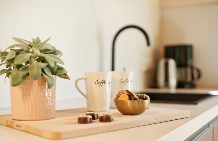 Detail van koffiemokken en lekkernijen in de keuken van Vakantiehuisje in Winterswijk.