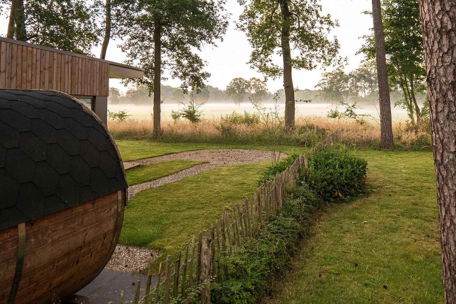 Geniessen Sie den ruhigen Garten und die Sauna in der Holiday Villa Boslodge 2 in Kotten, Achterhoek, umgeben von nebliger Natur und ruhigen Aussichten.