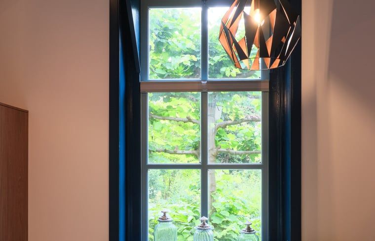 Gemuetlicher Innenbereich des Ferienhauses in Zelhem, Achterhoek, mit Blick auf die gruene Natur durch ein schoenes Fenster.