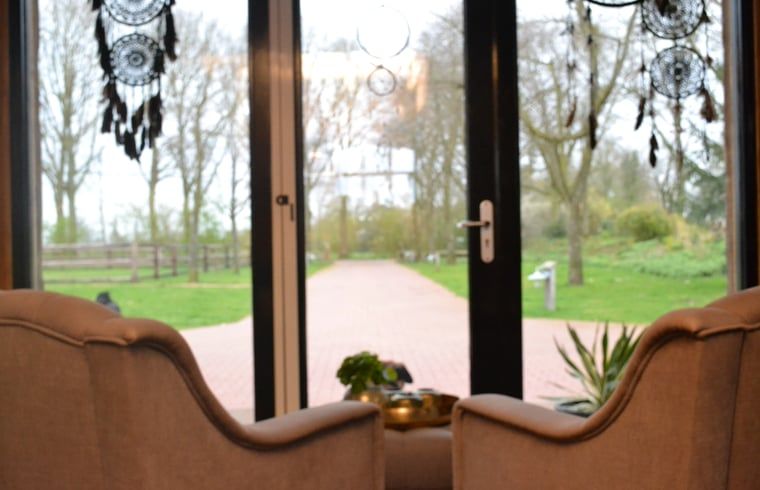 Gezellige zithoek met uitzicht op groene tuin in Vakantiehuisje in Ruurlo, Achterhoek, Gelderland. Ontspannen in landelijke omgeving.