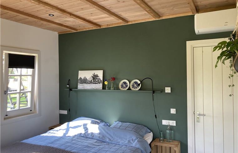 Cozy bedroom in Huisje in Westendorp, bed and breakfast in the Achterhoek, with wooden ceiling and soothing green walls.