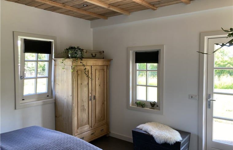 Bright room at Huisje in Westendorp, bed and breakfast in Gelderland, with wooden wardrobe and garden views.