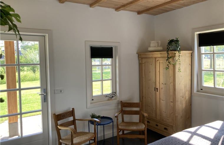 Cozy sitting area in Huisje in Westendorp, bed and breakfast in the Achterhoek, with wooden chairs and views of greenery.