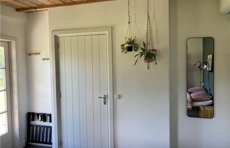 Entrance to Cottage in Westendorp, bed and breakfast in Westendorp, with stylish wooden door and hanging plants.