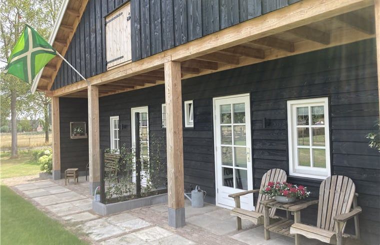 Veranda at Huisje in Westendorp, a bed and breakfast in Gelderland, with comfortable chairs and flag of the Achterhoek.