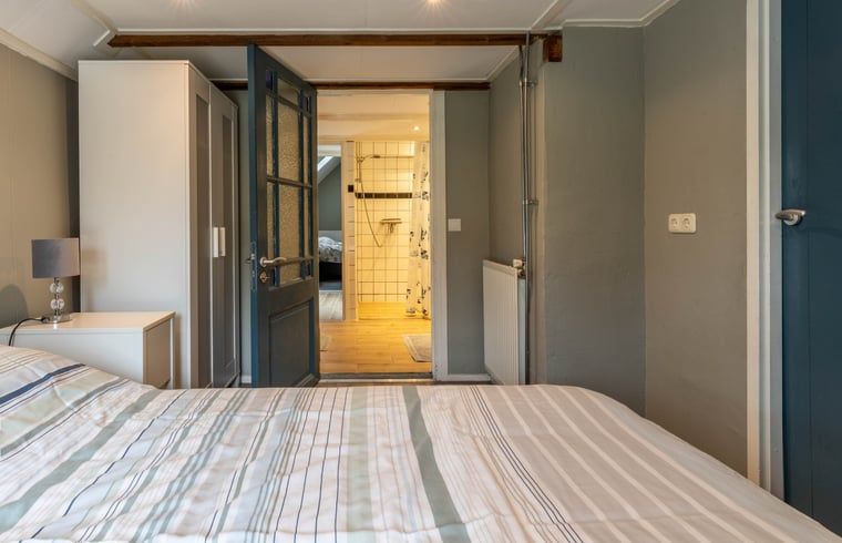 Slaapkamer met ensuite badkamer in Huisje in Aalten, vakantiehuis in de Achterhoek, voor extra comfort.