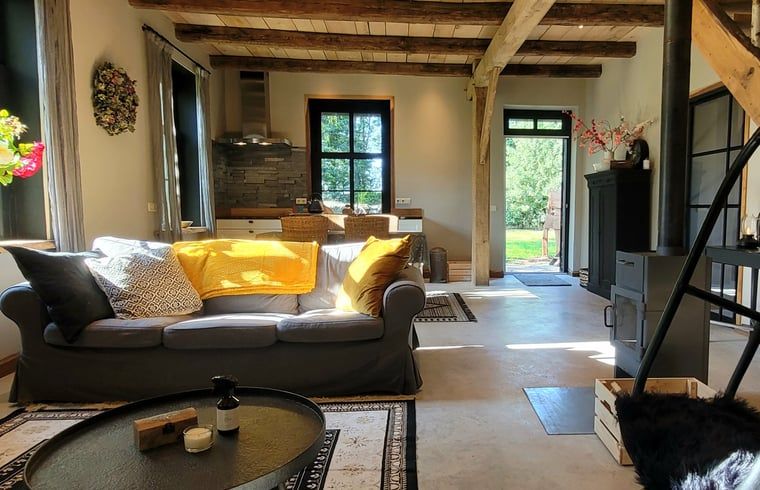 Gemuetliches Wohnzimmer im Ferienhaus in Vragender, Achterhoek, mit bequemem Sofa und Holzbalken.
