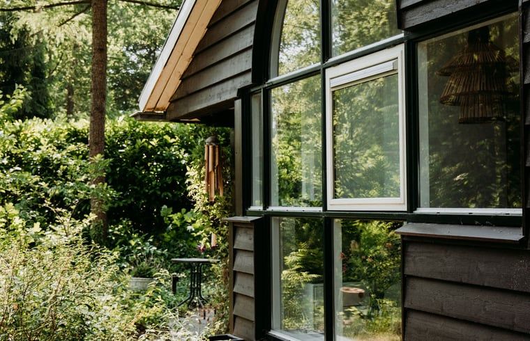 Zijaanzicht van vakantiehuis in Lochem, omgeven door groen en rust.