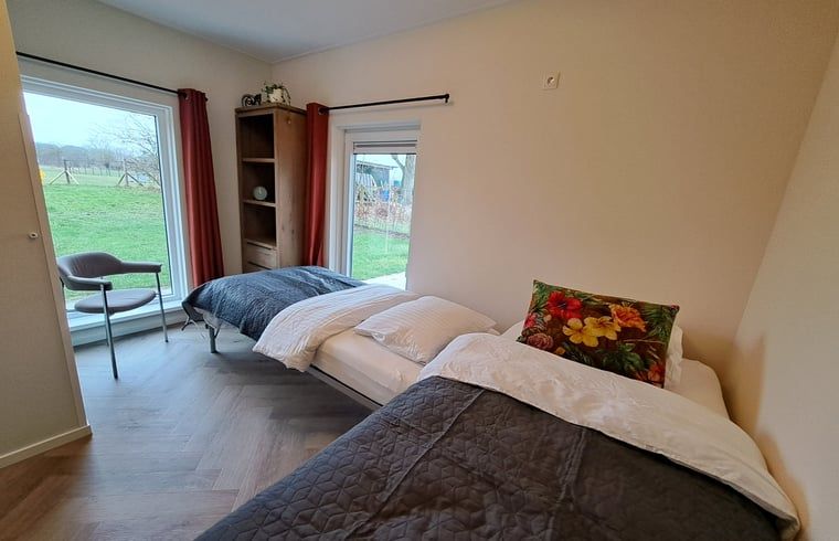 Tweepersoonsbed in Vakantiehuisje in Lochem met uitzicht op de groene omgeving van de Achterhoek, Gelderland.