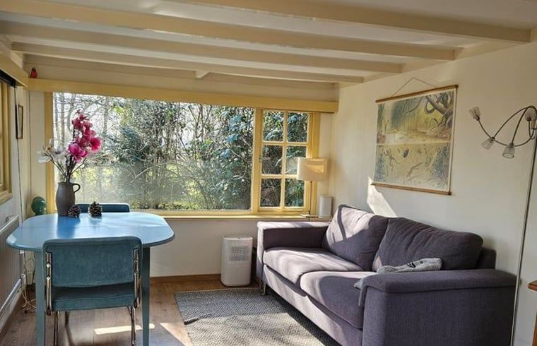 Gemuetliches Wohnzimmer des Ferienhauses in Harfsen, Achterhoek, Gelderland mit Blick in die Natur und bequemer Sitzecke.