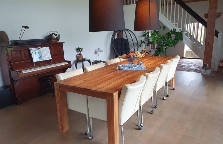 Ruime eetkamer in Vakantiehuis in Vorden Achterhoek, Gelderland, met houten tafel en piano, ideaal voor een ontspannen verblijf.